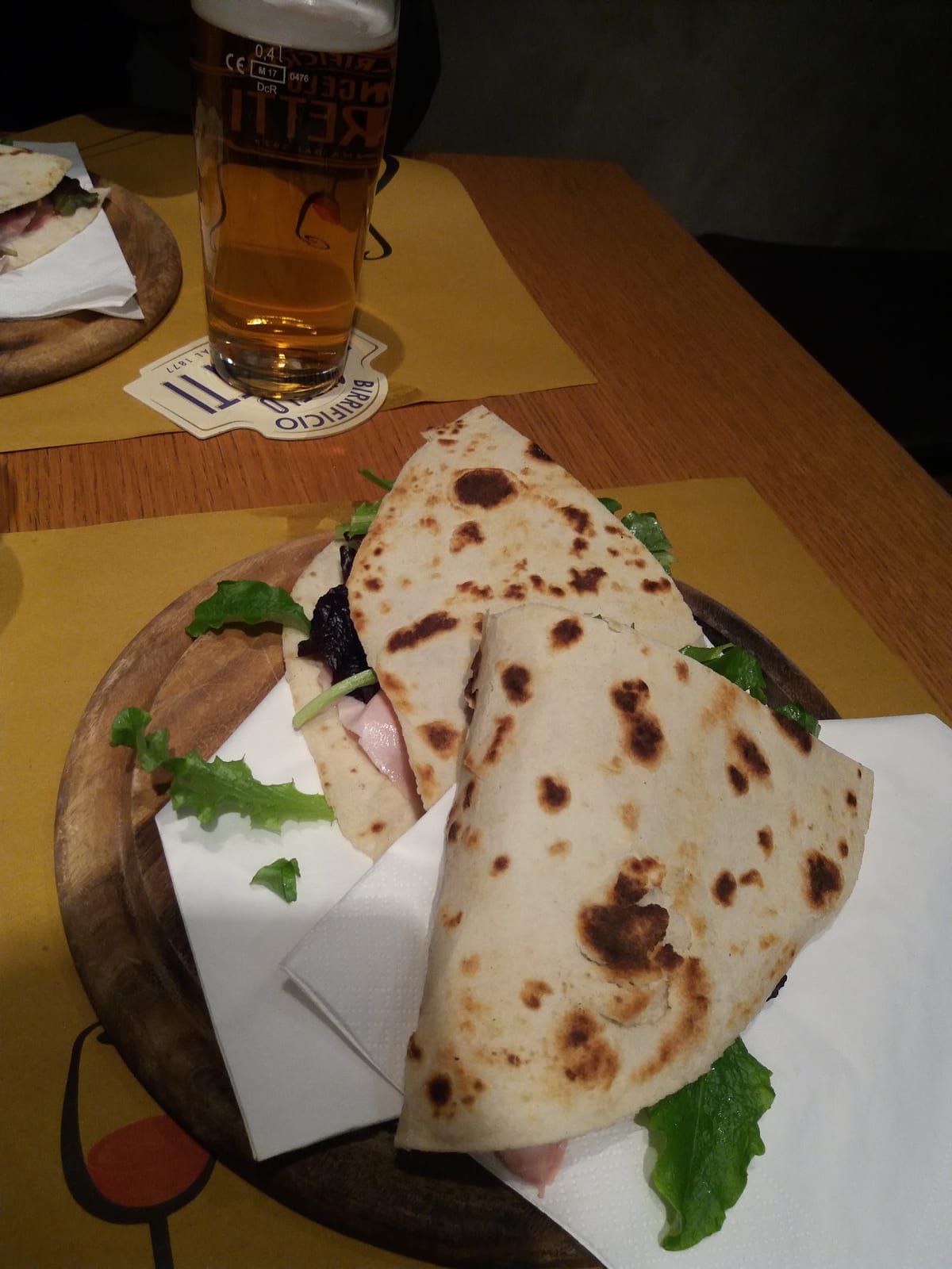 Due piadine farcite su tagliere di legno accanto a una birra artigianale