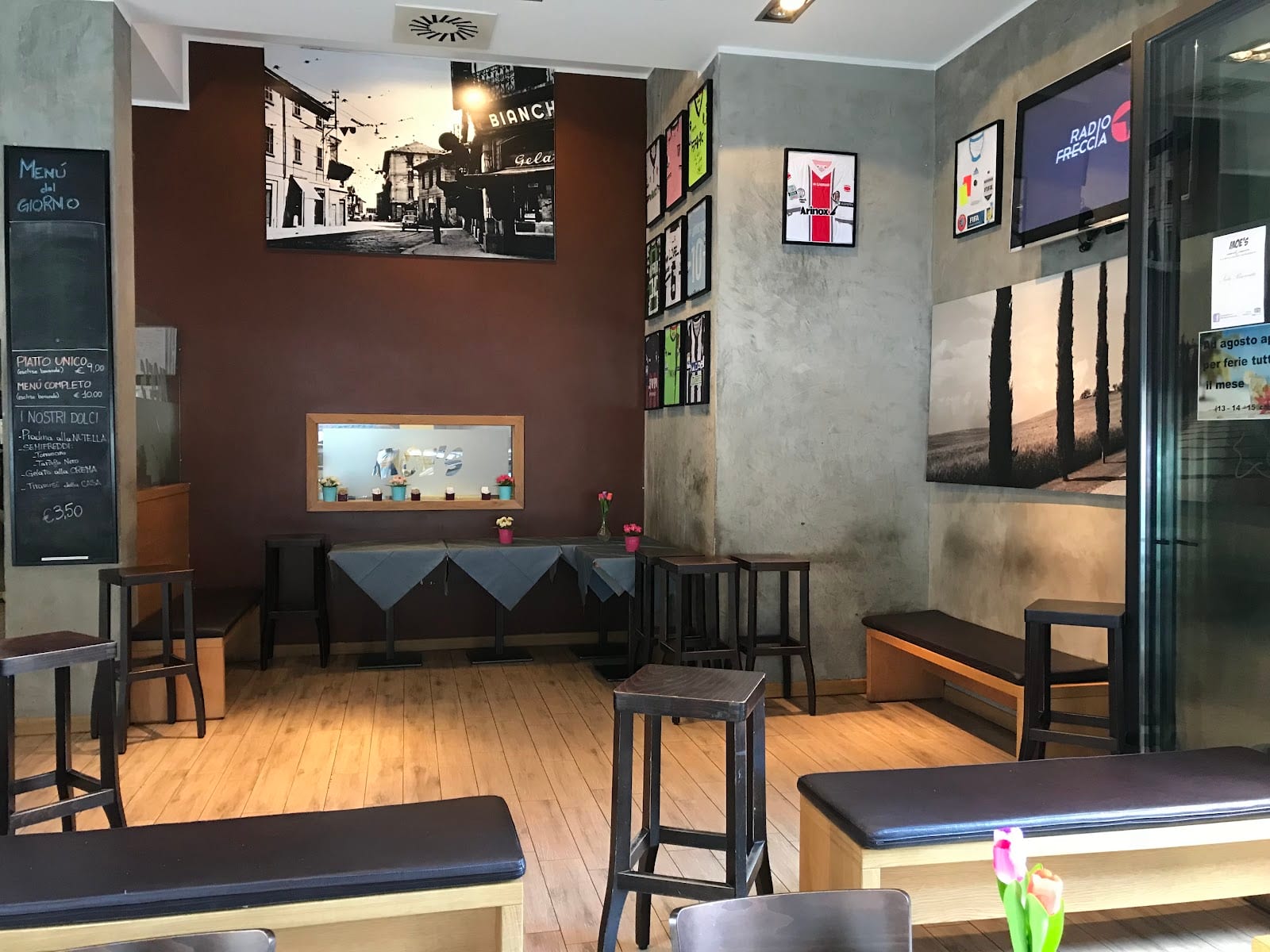 La sala di Moe's con la lavagna del menù del giorno, le maglie da calcio incorniciate e la foto d'epoca di Niguarda