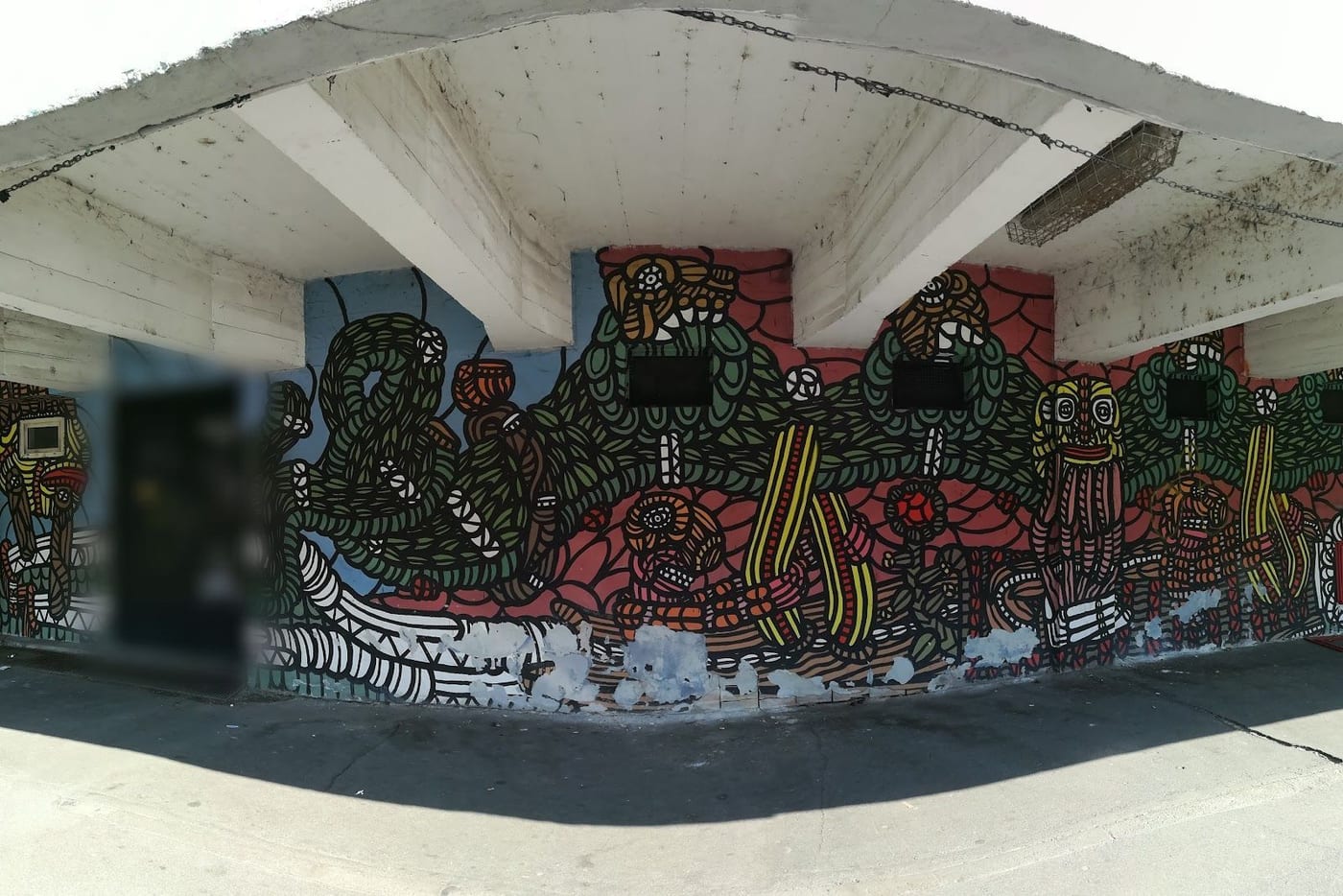 Il murale a linee nere, verdi e rosse sotto il porticato