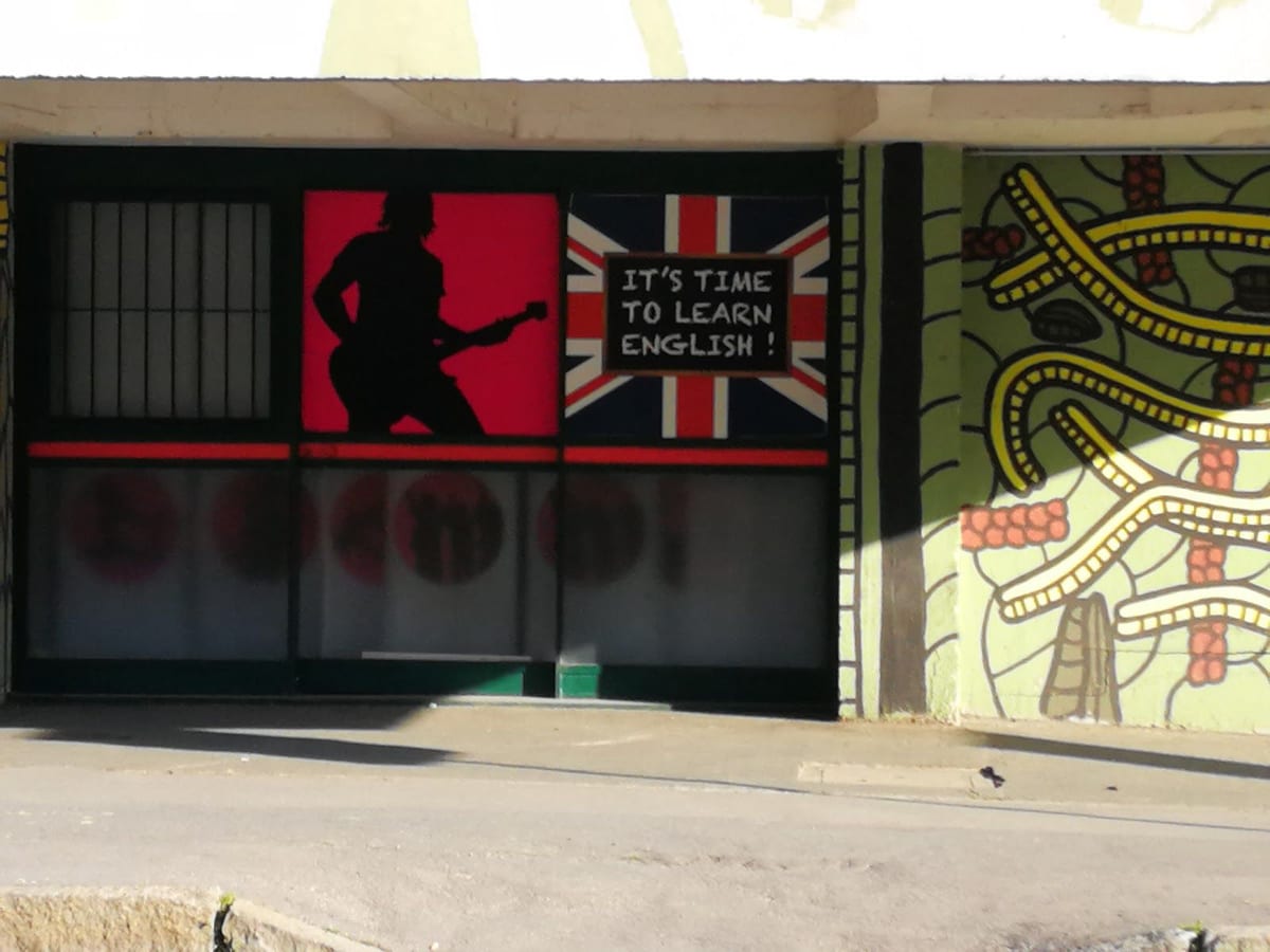La vetrina con la sagoma di un chitarrista e la scritta «It's time to learn English!» sulla bandiera inglese