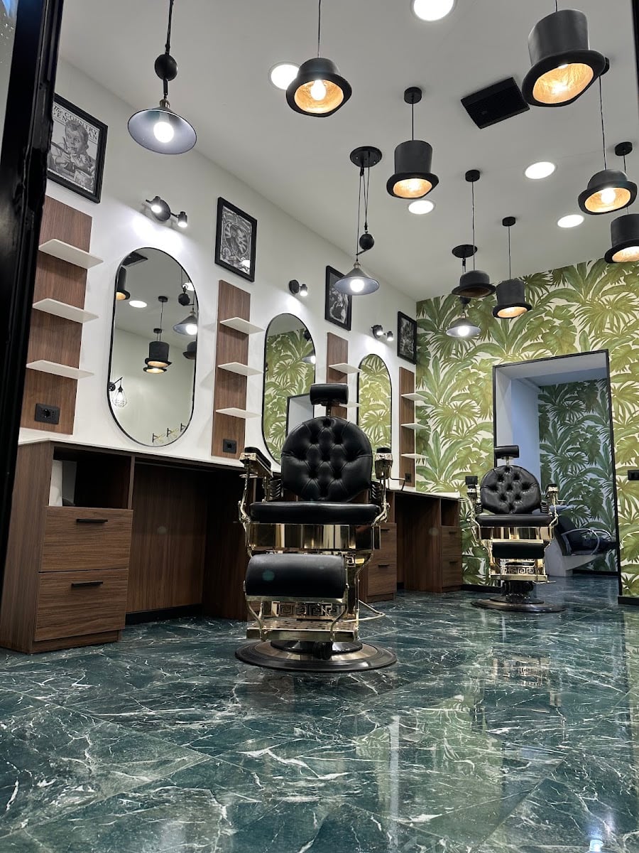 Interno Nabil's Barbershop: poltrone barbiere in ottone, parete botanica e pavimento in marmo verde