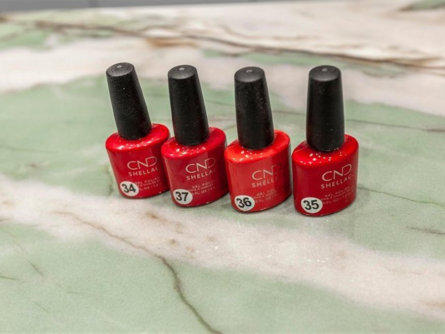 Smalti rossi CND numerati sul banco in marmo verde