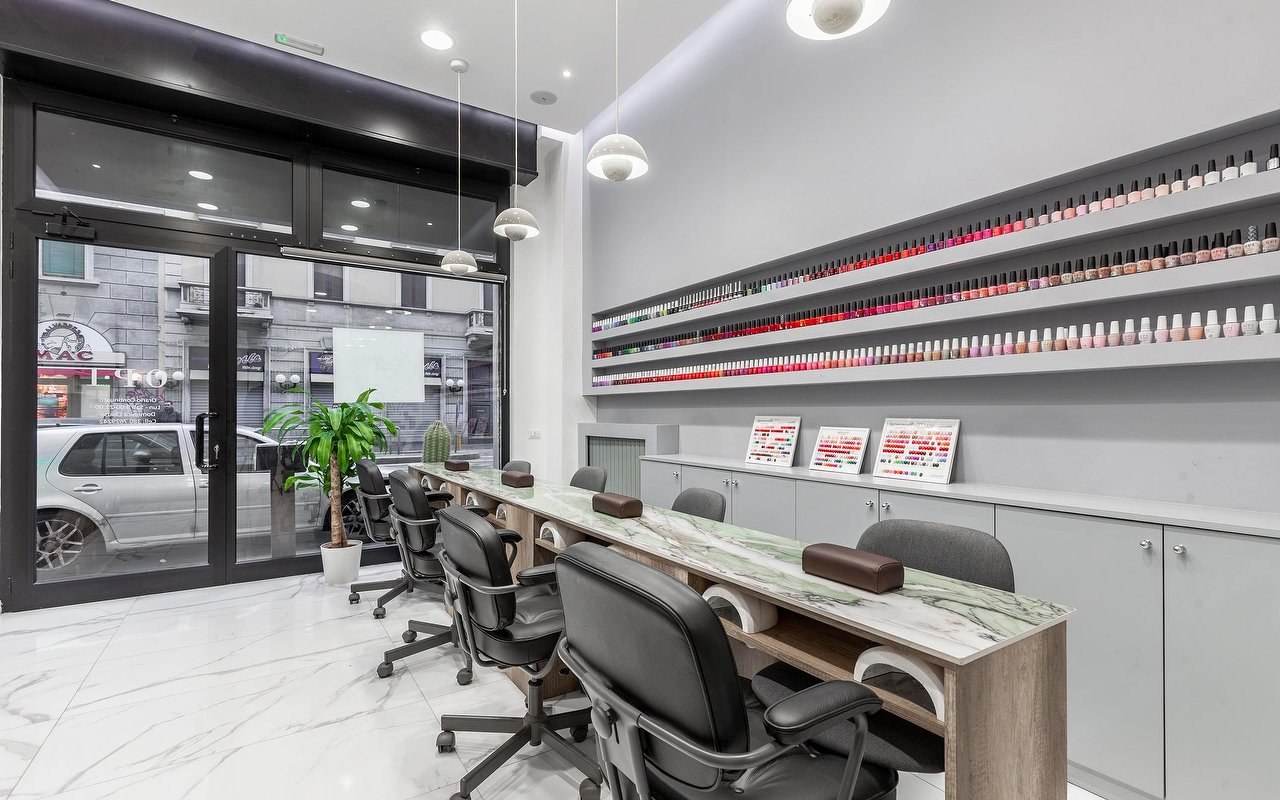 L'interno di Nail Studio N.2: postazioni manicure in marmo verde e pareti di smalti colorati