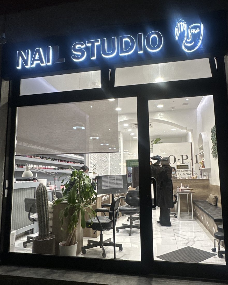 La vetrina di sera con l'insegna luminosa Nail Studio