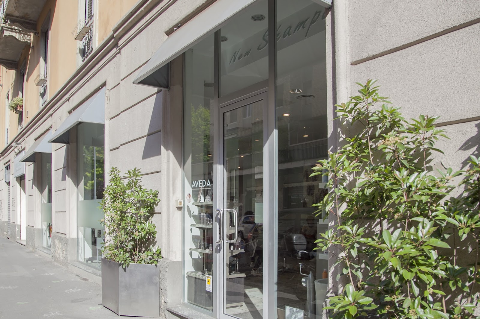 La vetrina di New Shampoo in via Lambro 9: facciata chiara, insegna Aveda e la scritta New Shampoo sul vetro