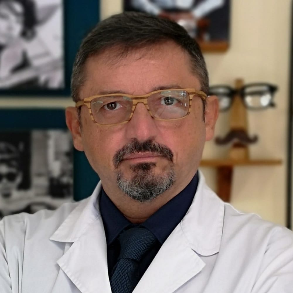 Maurizio Bondoni in camice bianco davanti alle montature del negozio