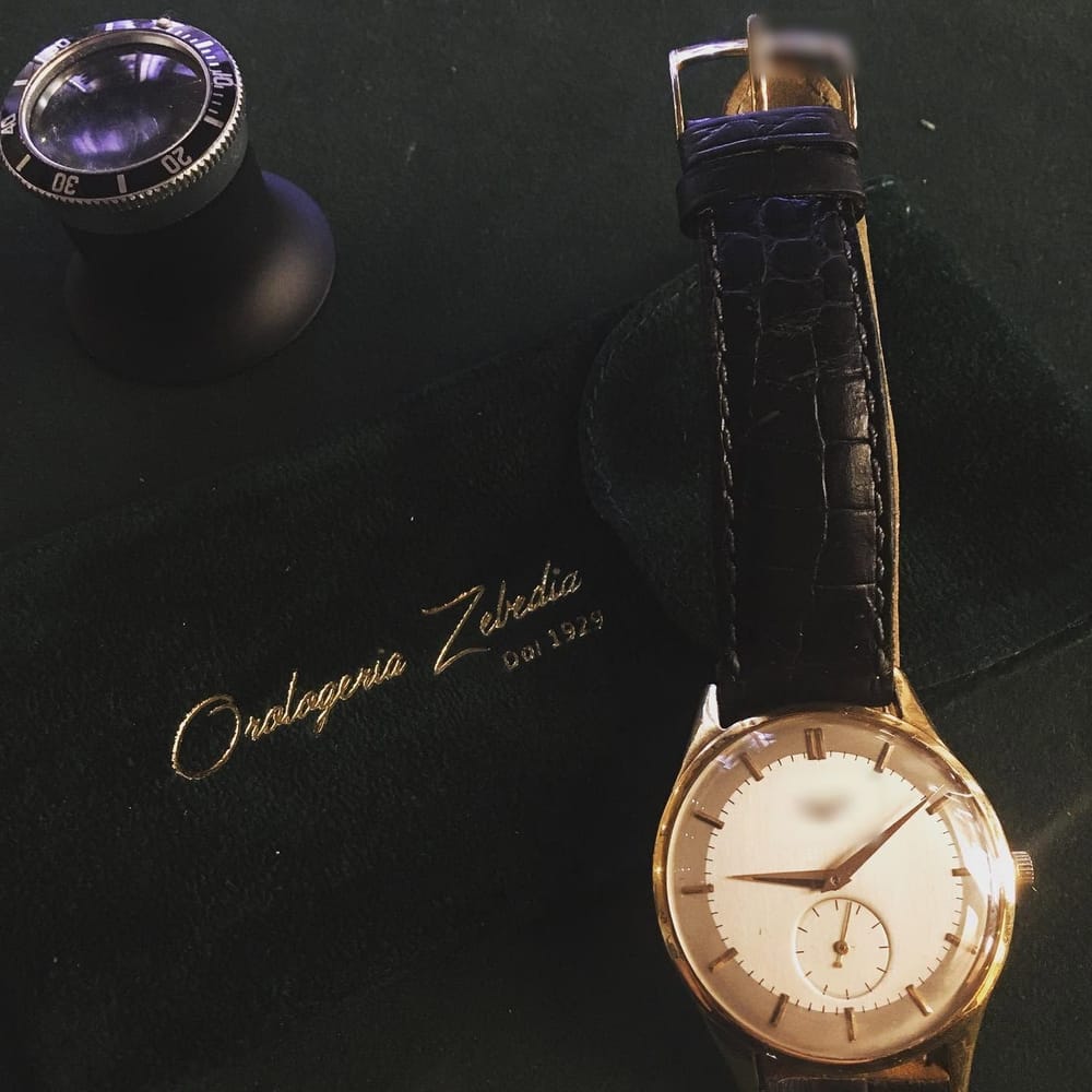 Un orologio d'oro degli anni '60 col cinturino in coccodrillo, la lente.