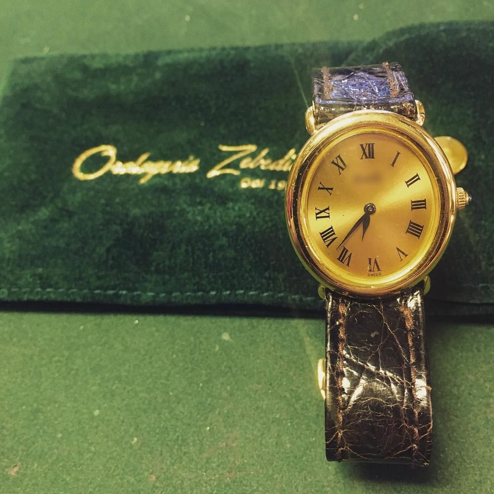 Un orologio ovale d'oro a carica manuale, coi numeri romani.