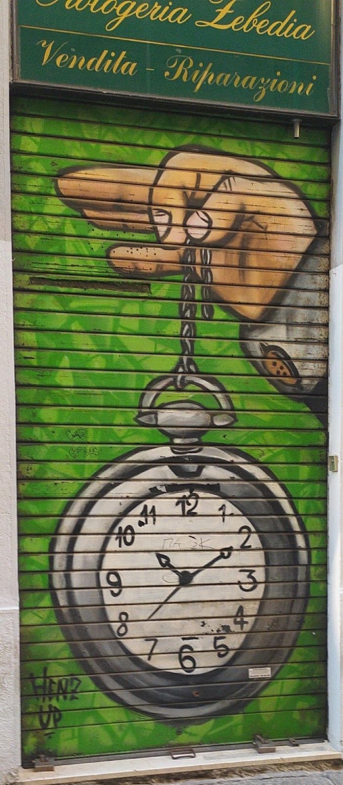 La nostra saracinesca dipinta di verde: una mano che regge un orologio da tasca per la catena; sopra, l'insegna.
