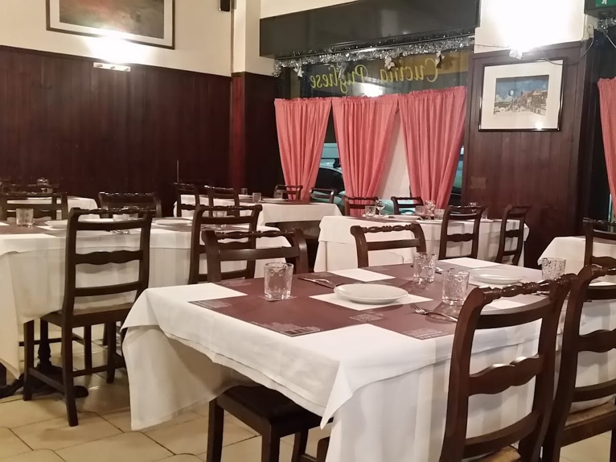 La sala dell'Osteria dei Mosaici, tovaglie bianche e tende rosse