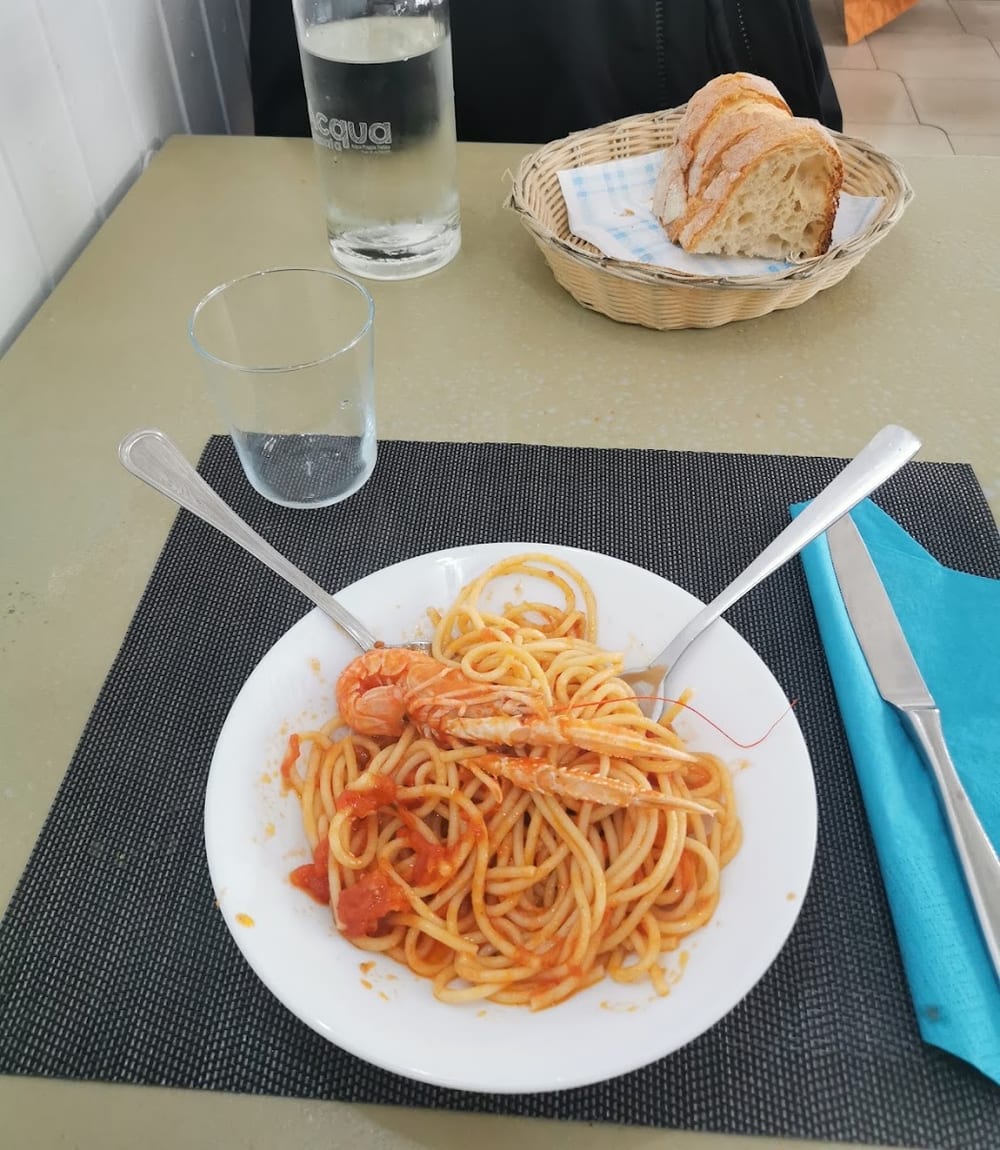 La tavola apparecchiata del pranzo: pane, acqua e un piatto di pasta al pomodoro