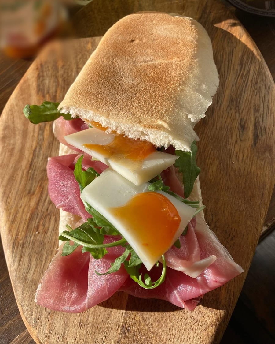 Crudo, rucola e formaggio con una composta arancione, sul tagliere.