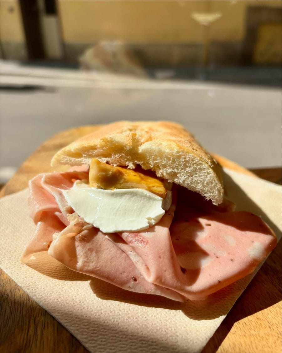 Mortadella e burrata nel pane, sul tagliere col tovagliolo.
