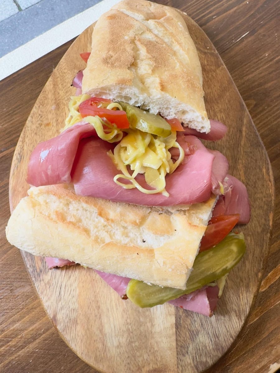 La carne a fette coi cetriolini, i datterini e un ripieno a fili nel pane, sul tagliere.