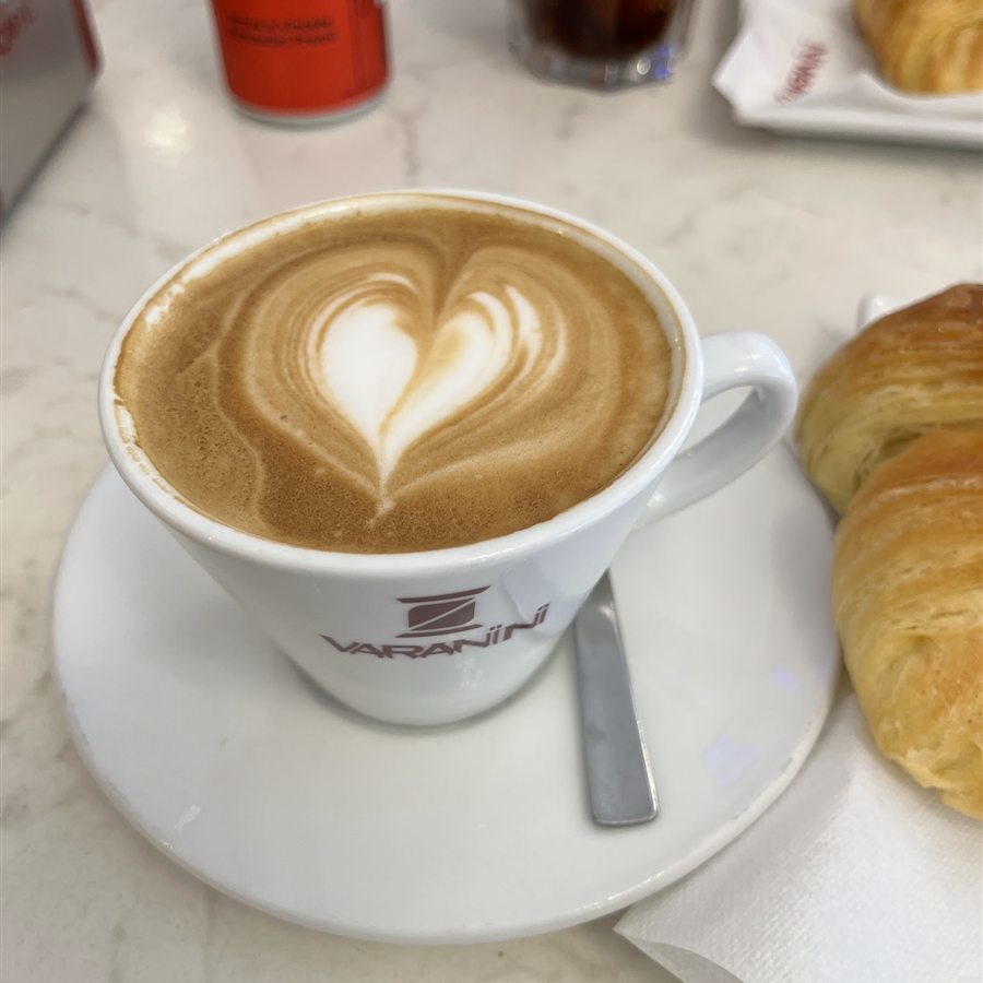 Cappuccino con latte art a cuore e brioche appena sfornata
