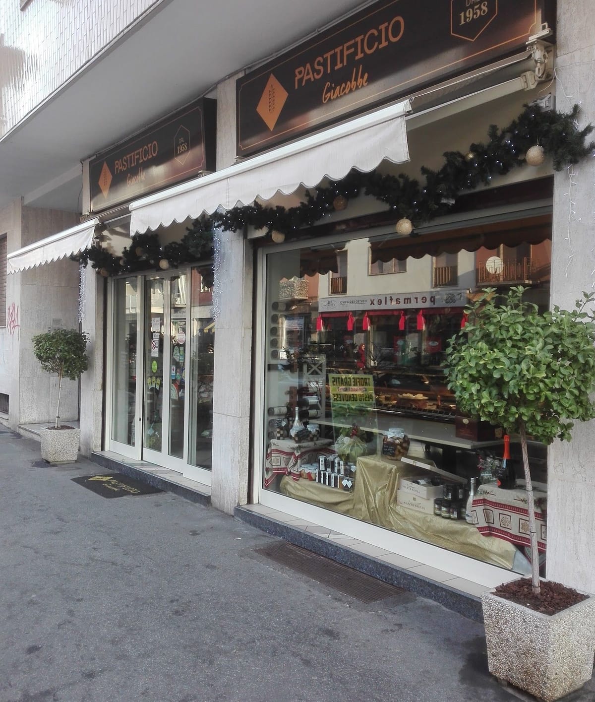 La facciata del pastificio in via Padova: l'insegna Pastificio Giacobbe, la tenda bianca e le vetrine con le ghirlande