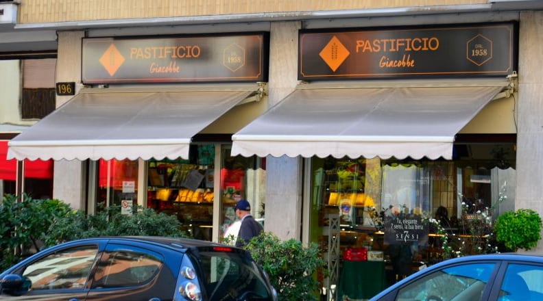 Le due insegne Pastificio Giacobbe dal 1958 sopra le tende bianche, con il civico 196