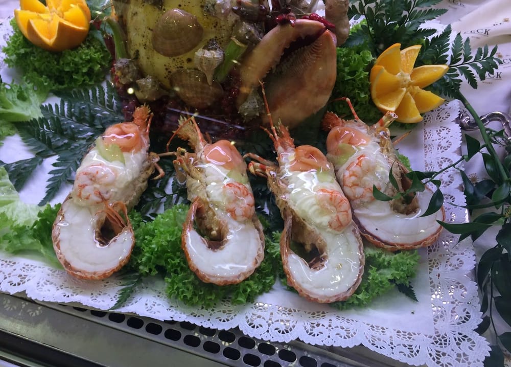 Scampi in bella vista su un centrino, con insalata e limone