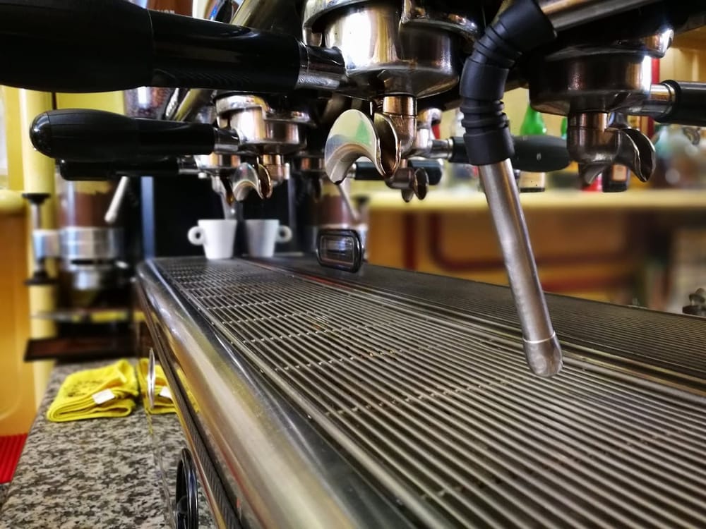 La macchina da caffè: i gruppi cromati, la lancia del vapore, la griglia e due tazzine.