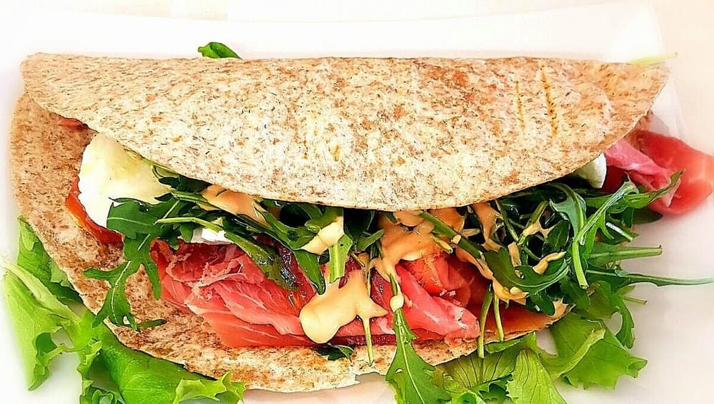 Una piadina integrale piegata col crudo, la rucola e la salsa.