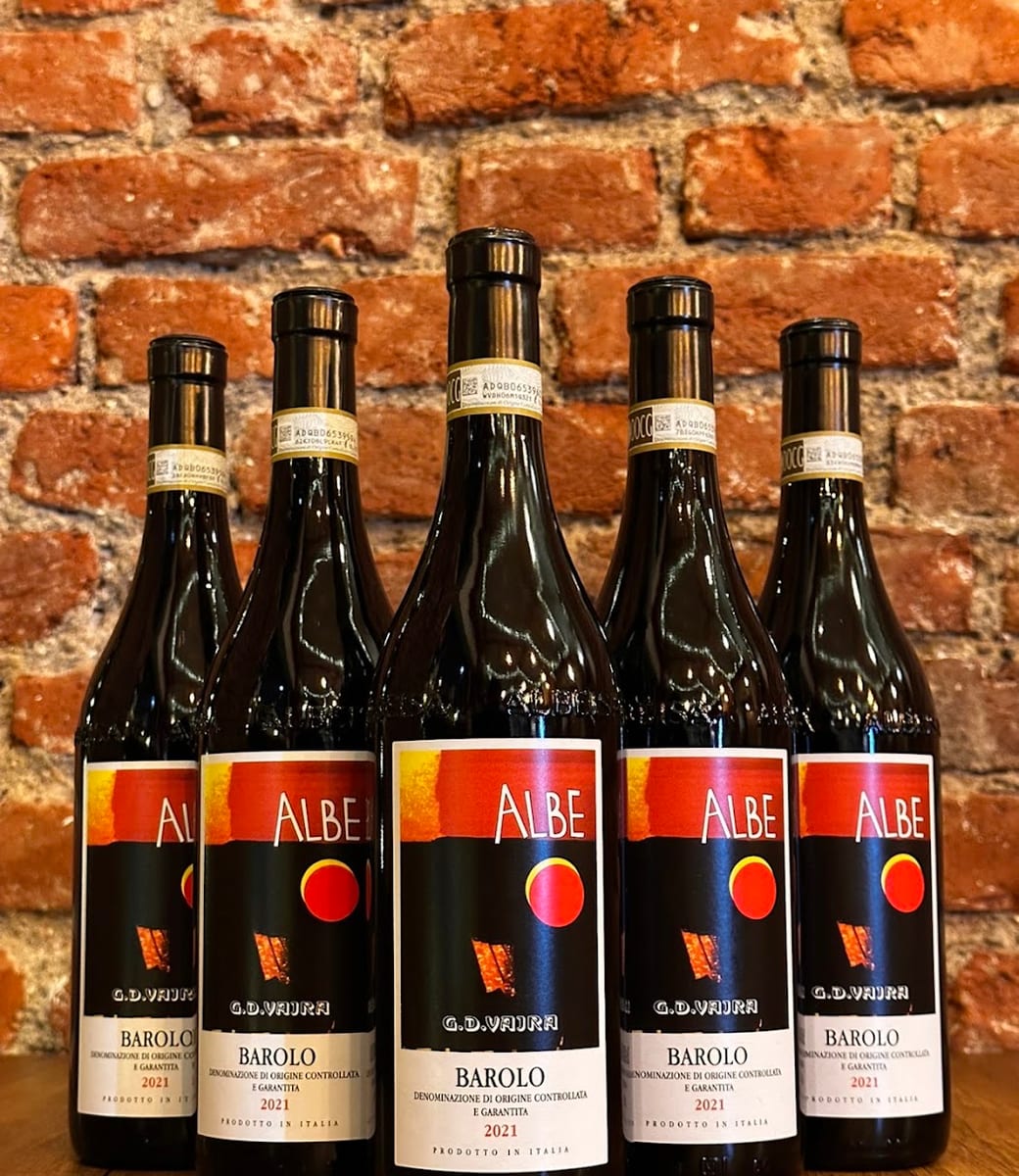 Bottiglie di Barolo Albe di G.D. Vajra contro il muro di mattoni