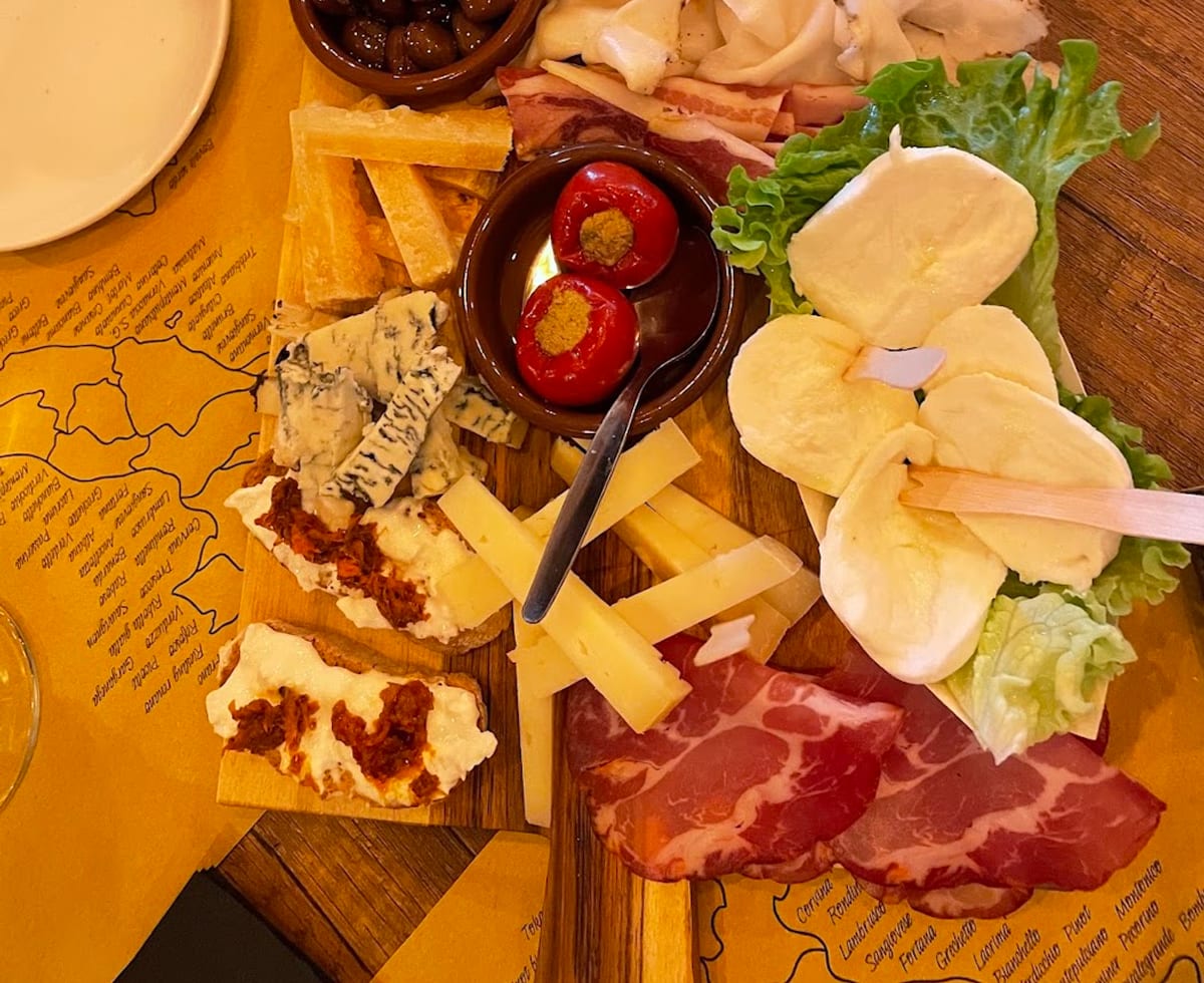Tagliere di salumi, formaggi, olive e crostini su tovaglietta a forma di mappa