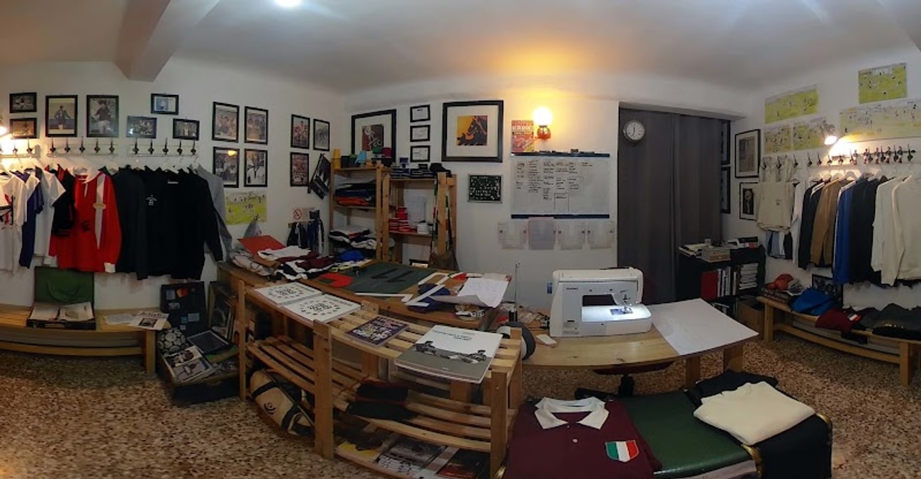 L'interno della sartoria: pavimento alla veneziana, maglie retrò appese, la macchina da cucire sul tavolo e le fotografie d'epoca incorniciate