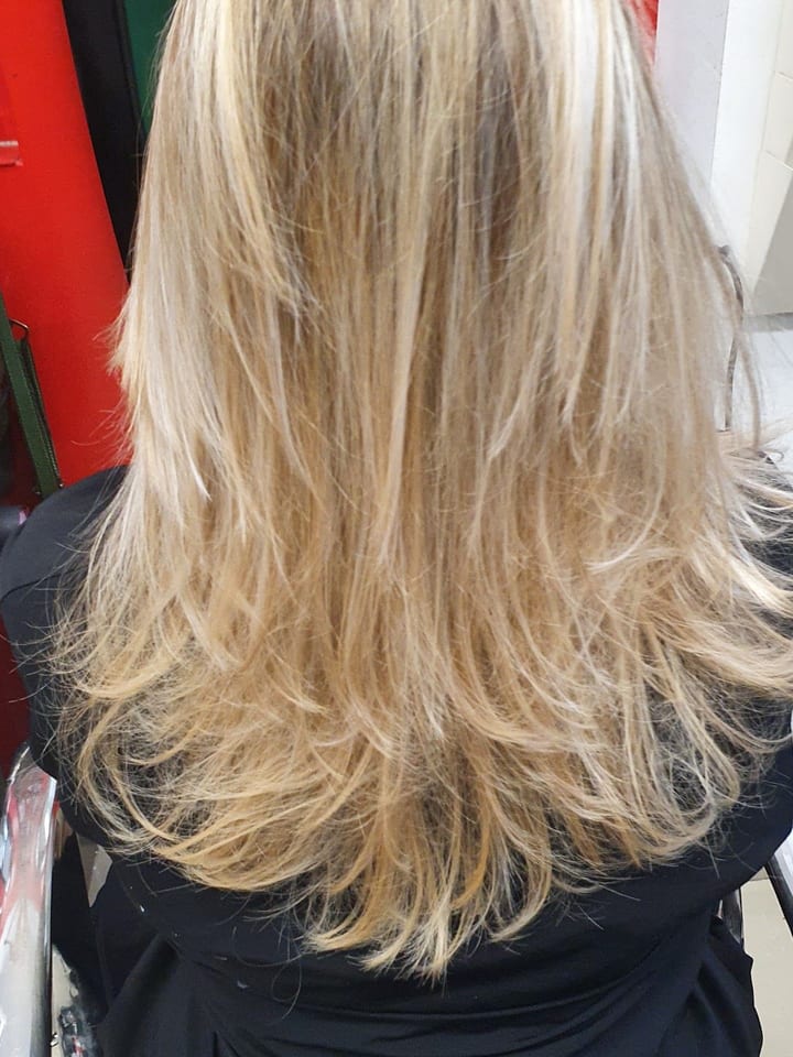 Capelli biondi lunghi e scalati, visti di spalle sulla poltrona.
