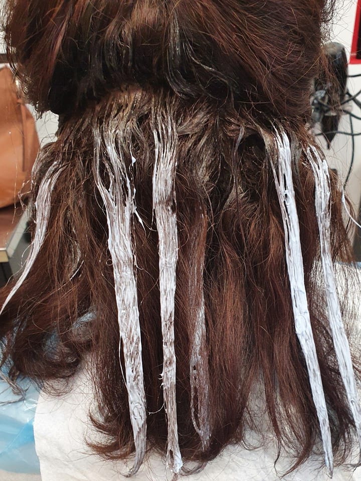 Capelli castani con i colpi di sole in posa sulle ciocche, visti di spalle.