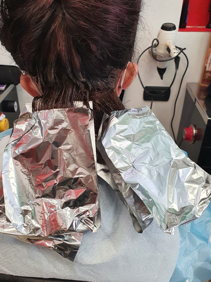 Il colore in posa, con le ciocche avvolte nelle stagnole, visto di spalle.