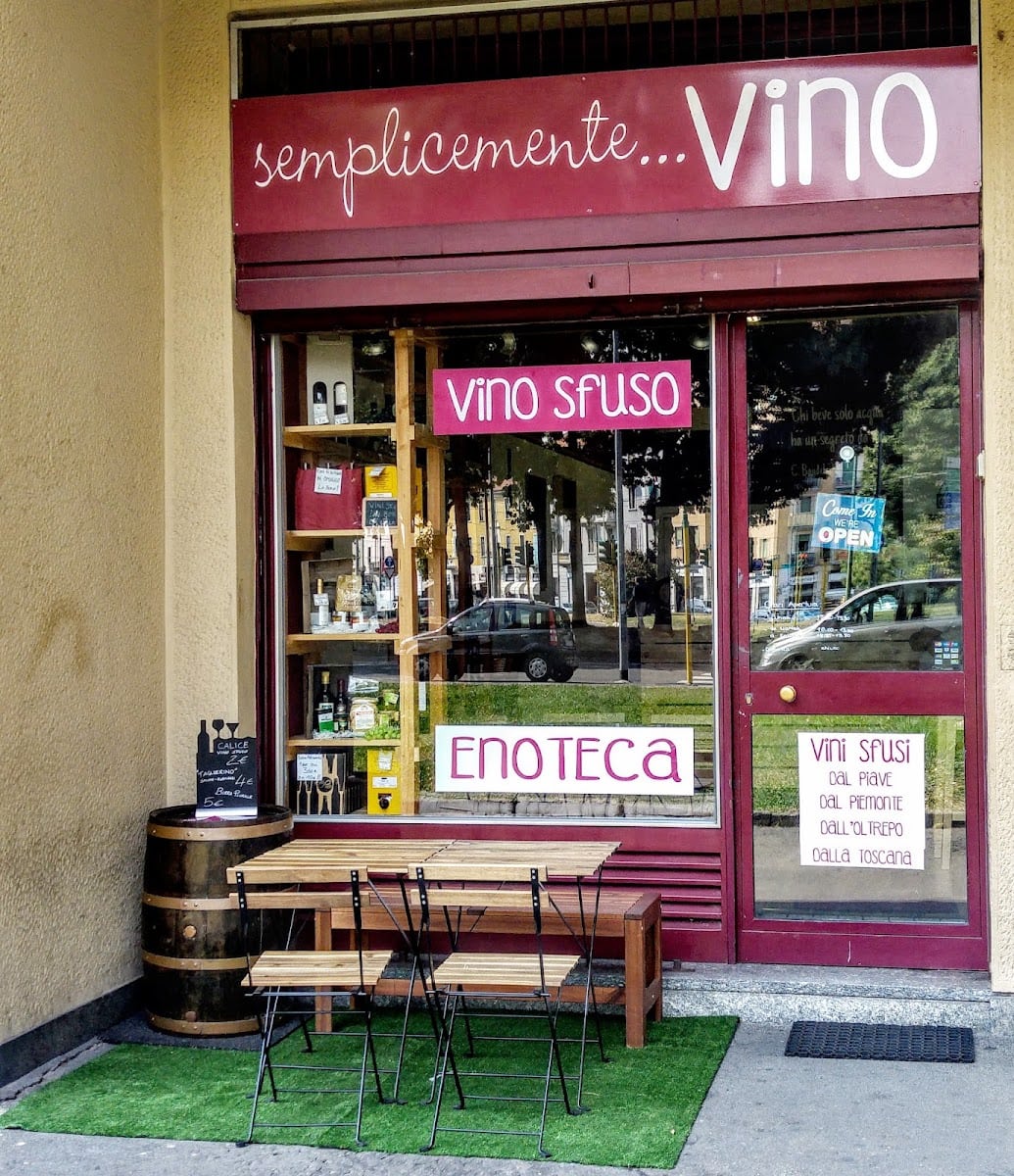 La vetrina di Semplicemente Vino con l'insegna, il vino sfuso e i tavolini fuori
