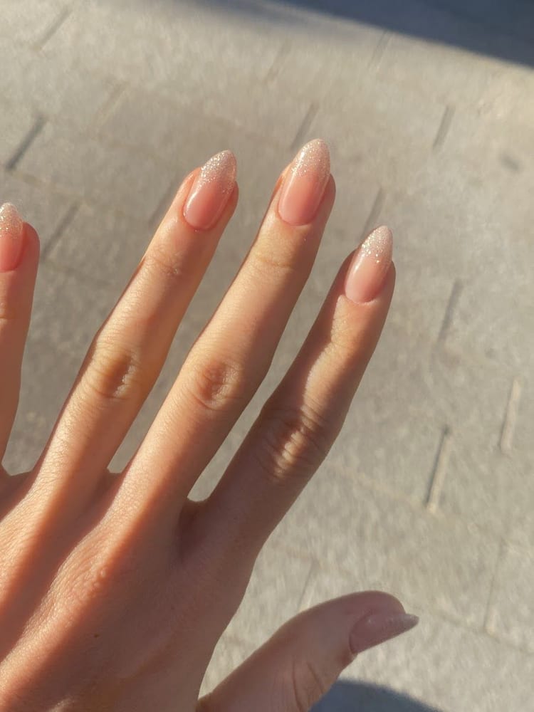 Unghie lunghe a mandorla color nude, la mano aperta.