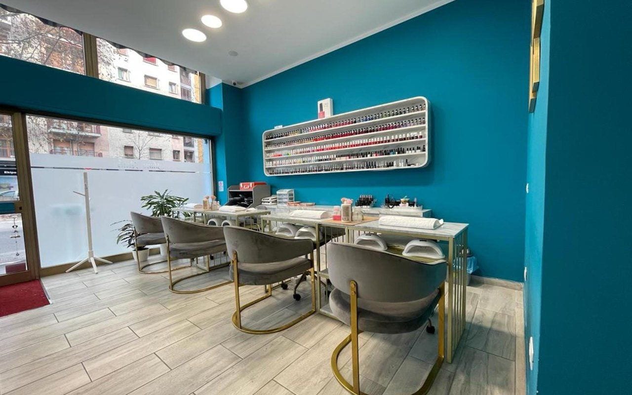 La sala: i tavoli di marmo lungo la vetrina satinata, le sedie di velluto grigio con le gambe dorate, la mensola degli smalti sulla parete petrolio.