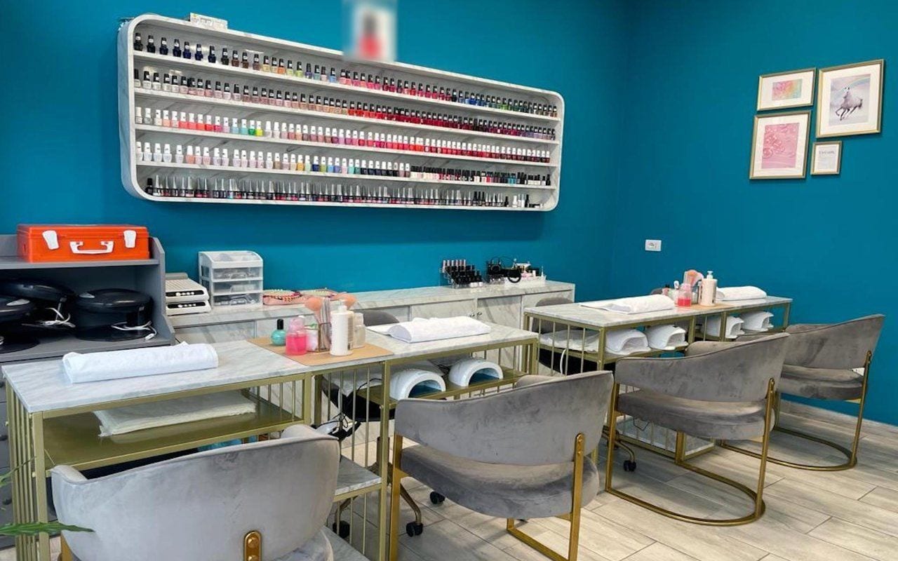 I tavoli manicure con le lampade bianche ad arco, e sopra la mensola degli smalti.