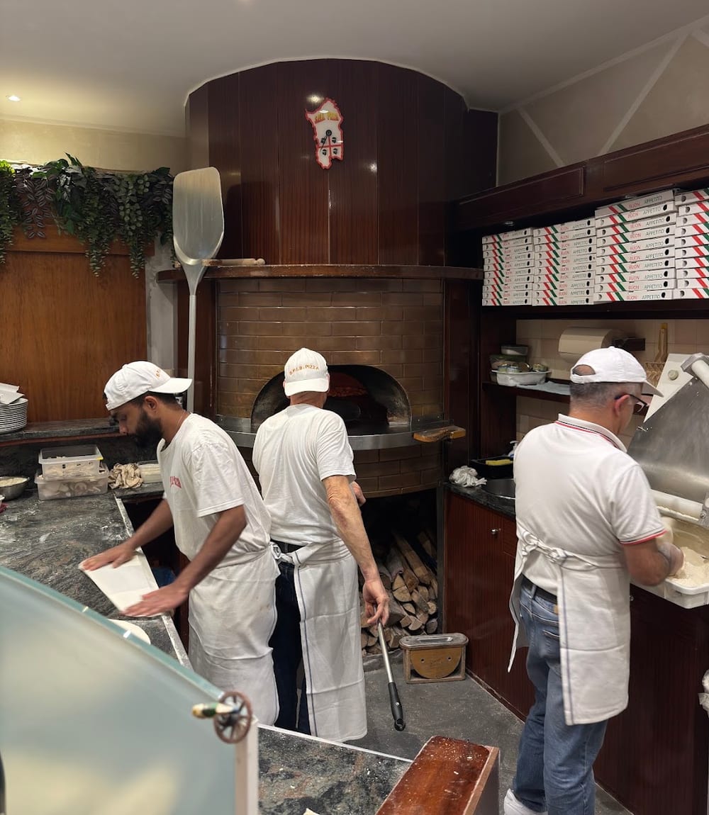 I pizzaioli al lavoro davanti al forno a legna
