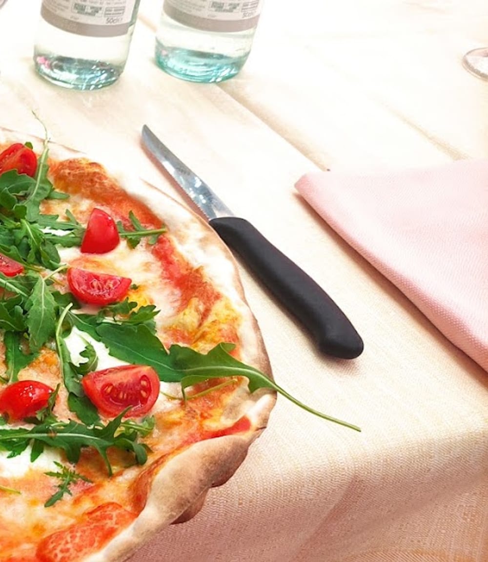 Una pizza sottile con rucola e pomodorini