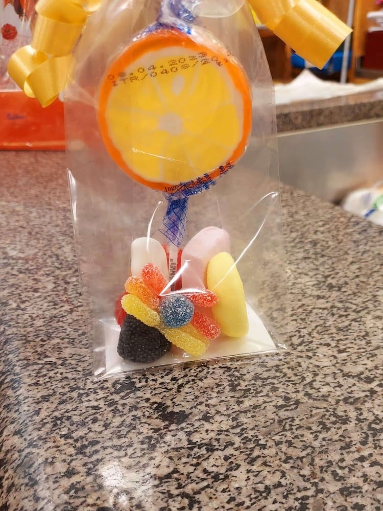 Un sacchetto col lecca-lecca all'arancia, gelatine zuccherate e marshmallow, sul granito.