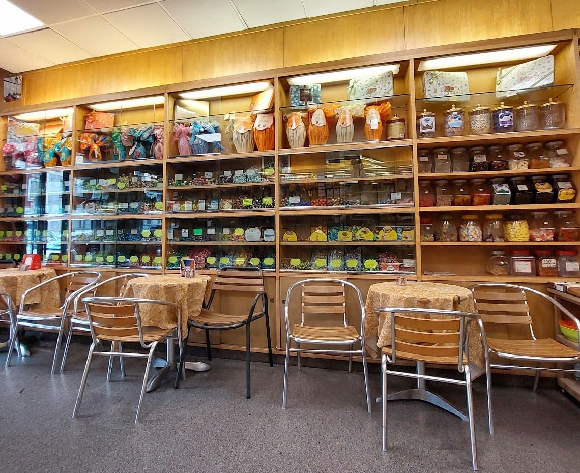La sala: la parete di legno con le caramelle nei vasi di vetro e le uova di Pasqua in cima, i tavolini con le tovaglie dorate e le sedie d'alluminio.