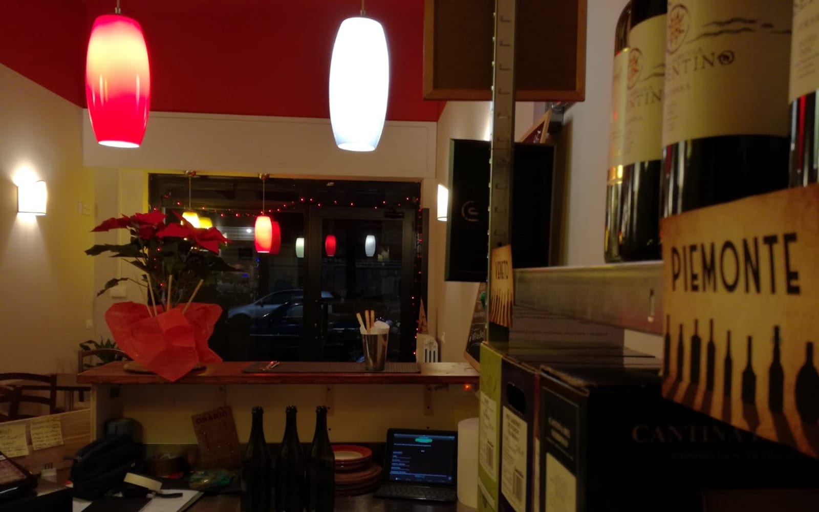 Il bancone della Vineria della Bovisa: pareti rosse, luci calde e i vini del Piemonte