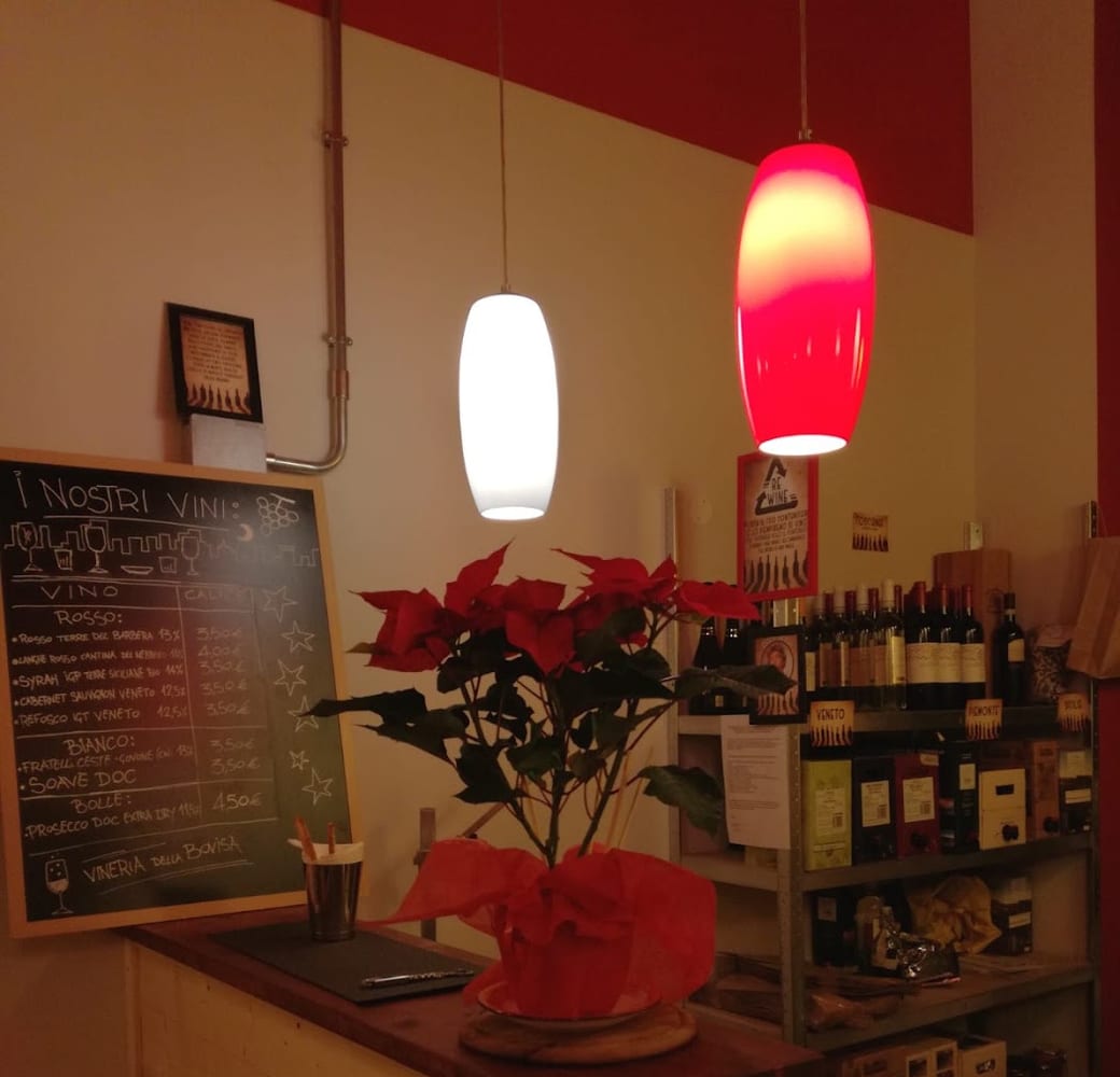 Gli scaffali dei vini e la lavagna della Vineria