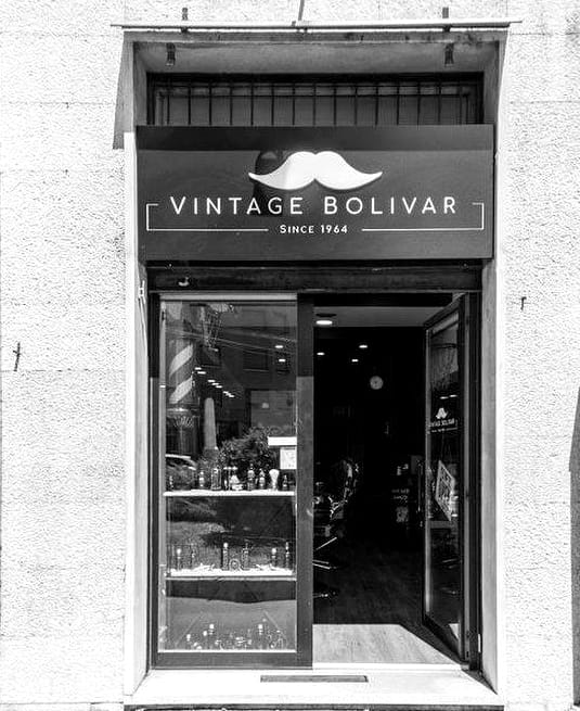 La facciata: l'insegna nera col baffo bianco, Vintage Bolivar e Since 1964, sopra la porta a vetri aperta e la vetrina
