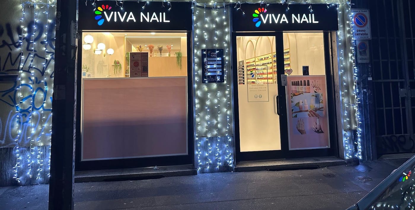 La vetrina di sera con l'insegna VIVA NAIL accesa e le luci di Natale